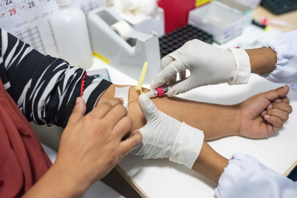 Nurse performing blood test procedure on patient in clinical setting.