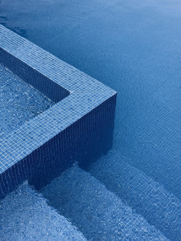 Abstract image of blue tiled pool edges with water ripples, exuding a minimalist and calming vibe.