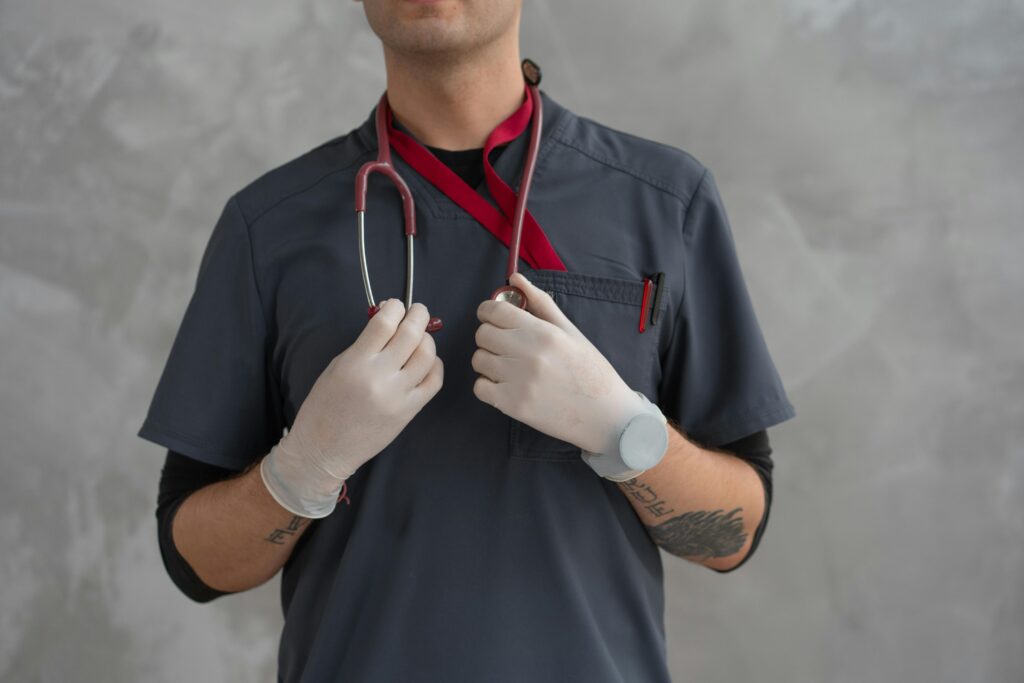 Close-up of a medical professional in scrubs with stethoscope and latex gloves.
